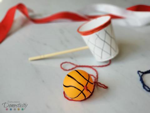 small ball connected by a string to a small cup on a stick