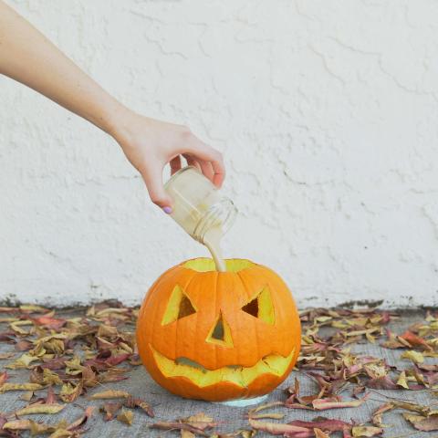 carved pumpkin with liquid being poured into