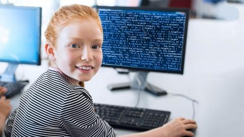 young red headed girl in front of a computer with coding