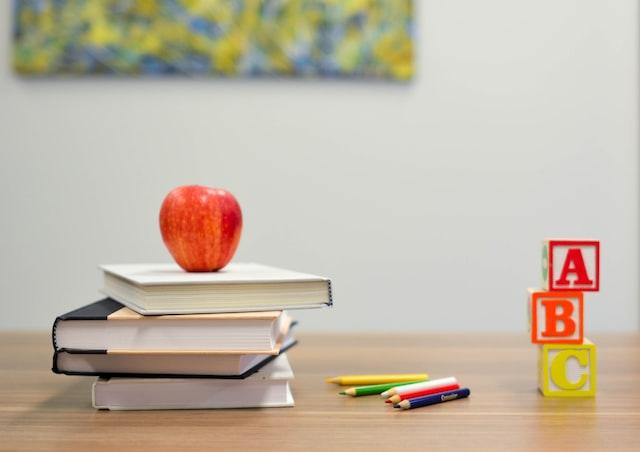 stacks of books with an apple on top on a table